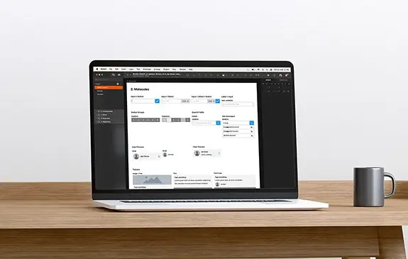 A notebook computer standing on a desk, showing the design software Sketch and pattern library template Atomic Sketch with a well-sorted overview of use interface components